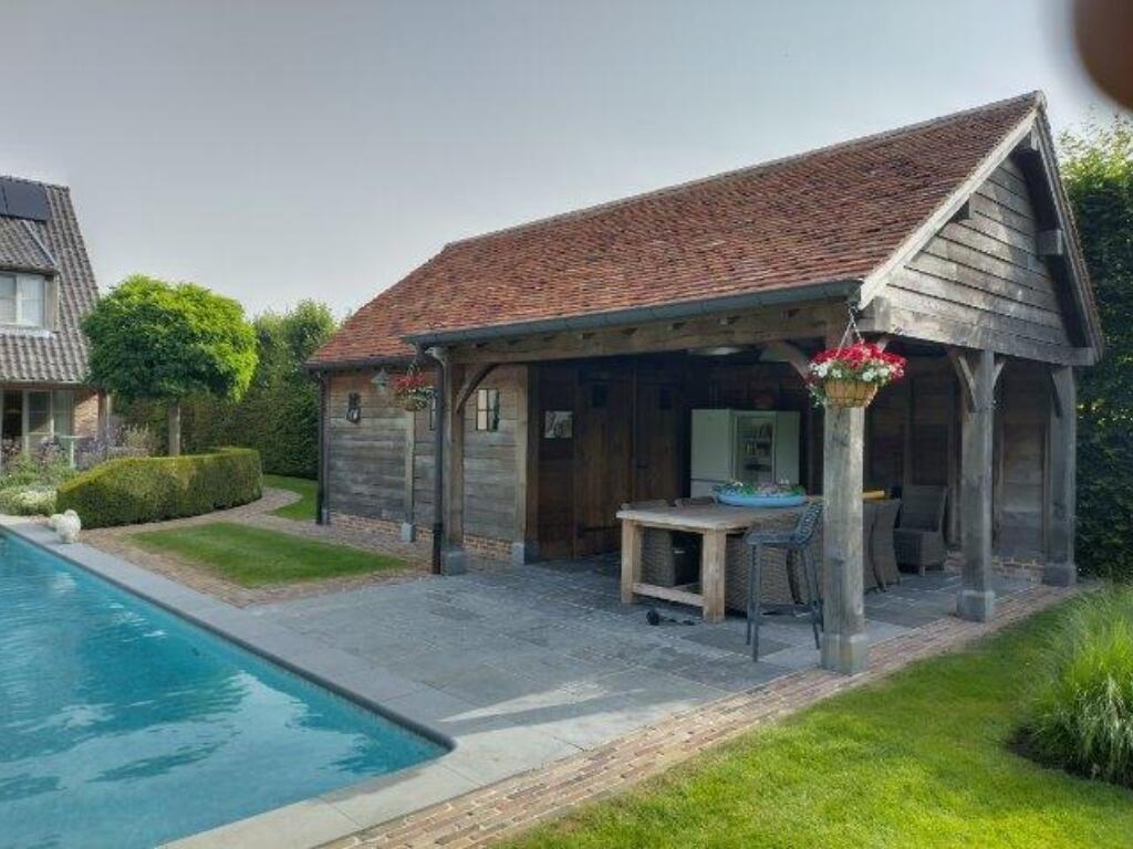 Zicht op het overdekt terras van dit landelijke eiken poolhouse